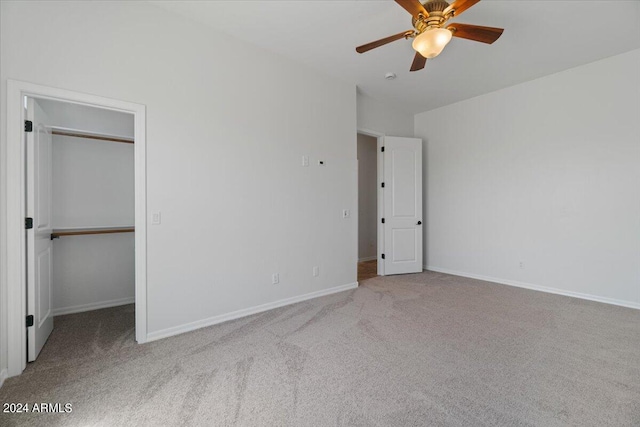 unfurnished bedroom featuring lofted ceiling, a closet, carpet, and ceiling fan