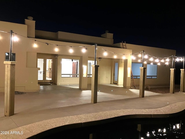 back house at night featuring french doors and a patio area