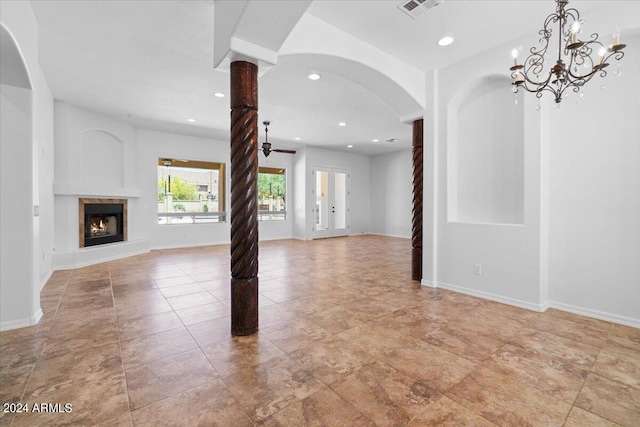 unfurnished living room with a notable chandelier, ornate columns, and light tile floors