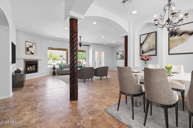 dining room with a notable chandelier, tile flooring, and decorative columns