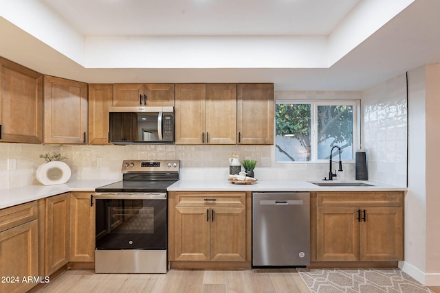 kitchen featuring backsplash, sink, light wood-type flooring, and appliances with stainless steel finishes