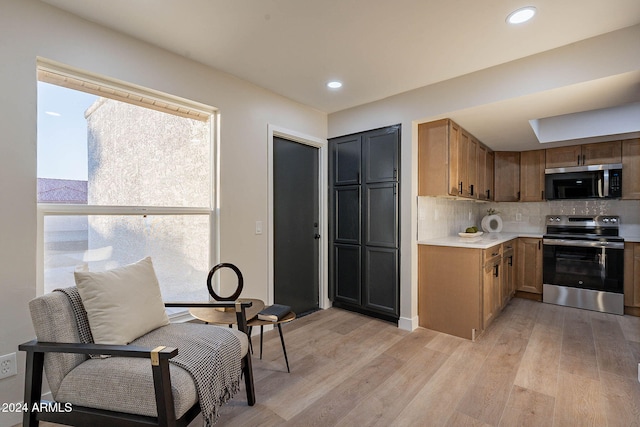 kitchen featuring decorative backsplash, light wood-type flooring, and appliances with stainless steel finishes