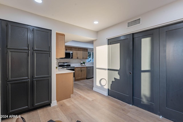 kitchen with backsplash, appliances with stainless steel finishes, and light hardwood / wood-style flooring