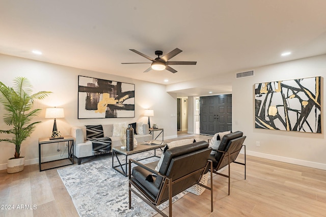 living room with light hardwood / wood-style flooring and ceiling fan