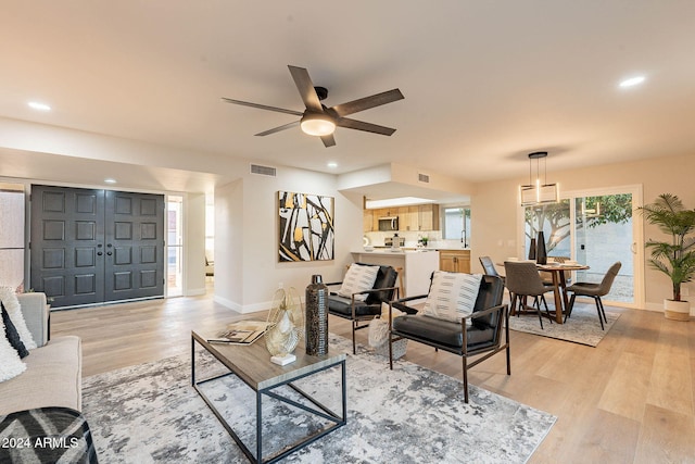 living room with ceiling fan and light wood-type flooring