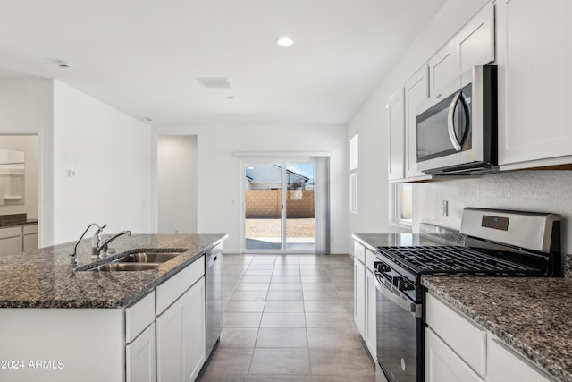 kitchen featuring sink, white cabinetry, dark stone counters, an island with sink, and stainless steel appliances