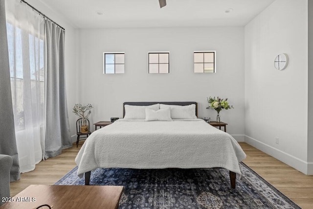 bedroom featuring ceiling fan, multiple windows, and wood-type flooring