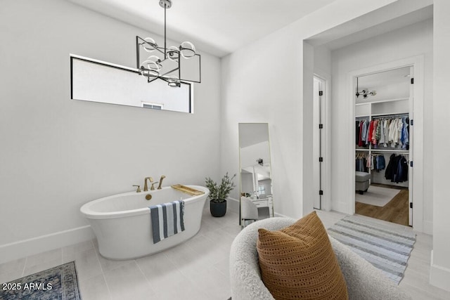 bathroom with tile patterned floors, a bathtub, and an inviting chandelier