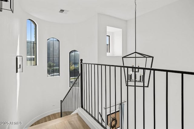 stairs featuring hardwood / wood-style flooring, plenty of natural light, and a chandelier