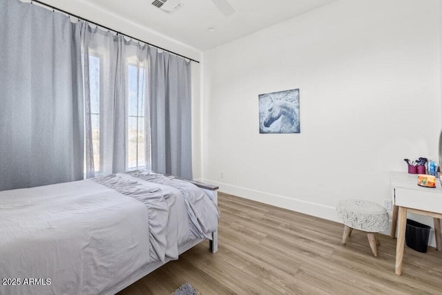 bedroom featuring ceiling fan, hardwood / wood-style floors, and multiple windows