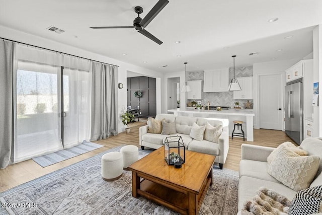 living room featuring light wood-type flooring and ceiling fan