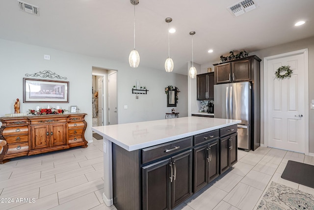 kitchen with decorative light fixtures, a center island, dark brown cabinetry, and stainless steel refrigerator