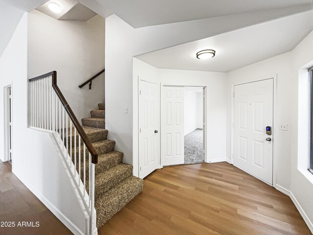 foyer entrance featuring stairs, wood finished floors, and baseboards