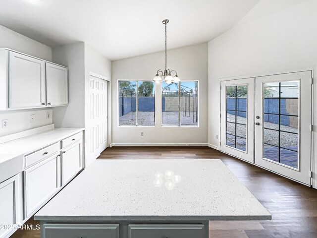 kitchen with a notable chandelier, hanging light fixtures, white cabinets, a kitchen island, and vaulted ceiling