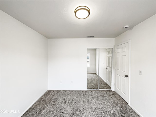 unfurnished bedroom with dark colored carpet, a closet, visible vents, and baseboards