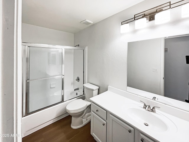 full bath featuring enclosed tub / shower combo, toilet, wood finished floors, visible vents, and vanity