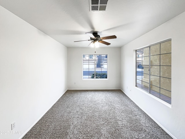 carpeted empty room with baseboards, a ceiling fan, visible vents, and a healthy amount of sunlight