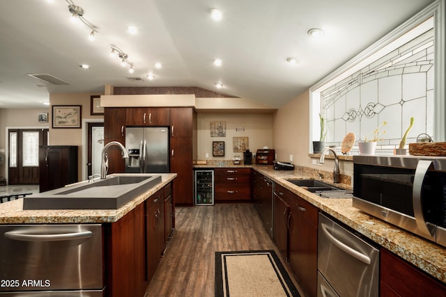 kitchen with a kitchen island with sink, sink, stainless steel appliances, and beverage cooler