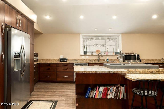 kitchen featuring light stone counters, stainless steel fridge with ice dispenser, light hardwood / wood-style floors, and sink