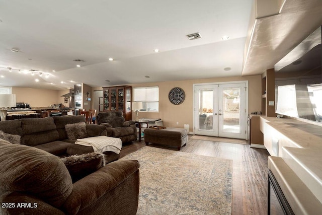 living room featuring french doors, vaulted ceiling, and light hardwood / wood-style floors