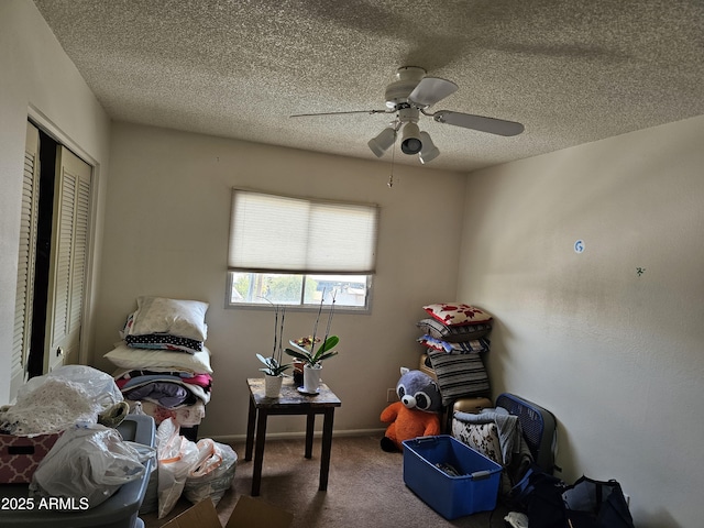 interior space with a textured ceiling, carpet, and ceiling fan
