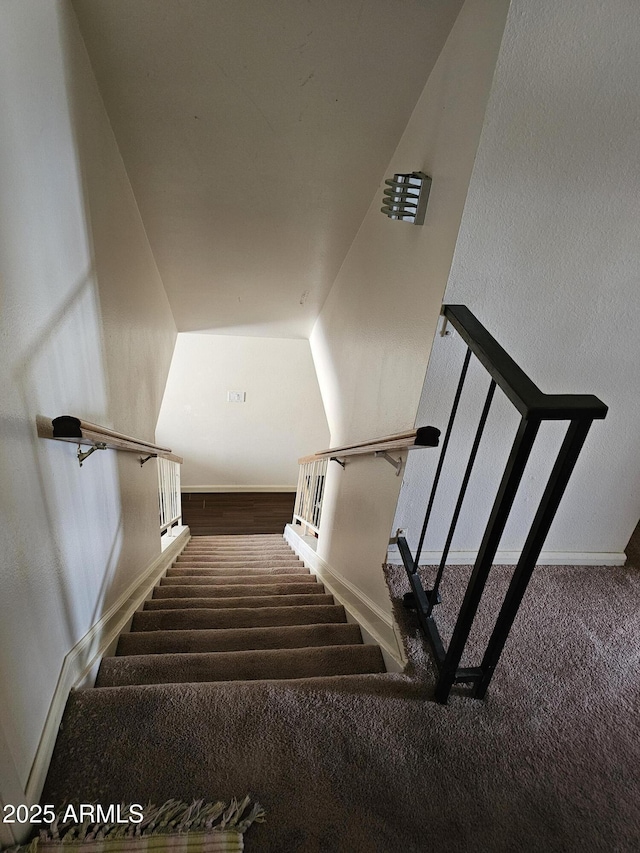 stairway featuring baseboards and carpet flooring