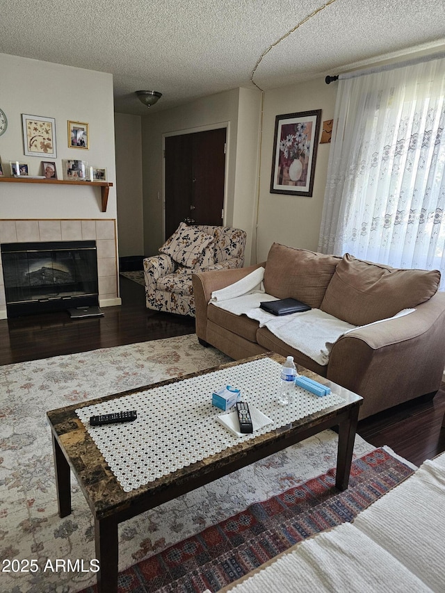 living area featuring a textured ceiling, wood finished floors, and a fireplace