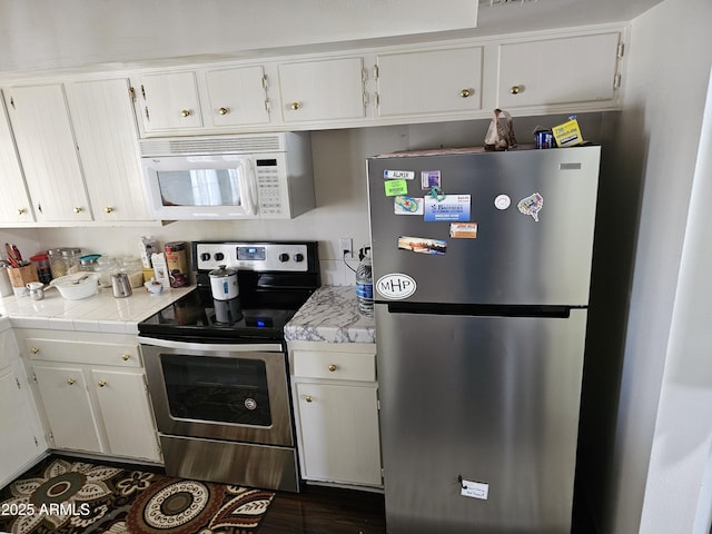 kitchen with dark wood-type flooring, white cabinets, and stainless steel appliances