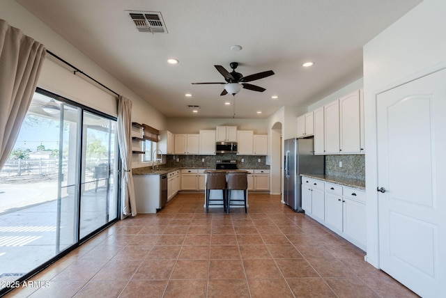 9998 W Prospector Dr, Queen Creek, AZ 85144 - kitchen featuring appliances with stainless steel finishes, a sink, tasteful backsplash, ceiling fan, and white cabinets