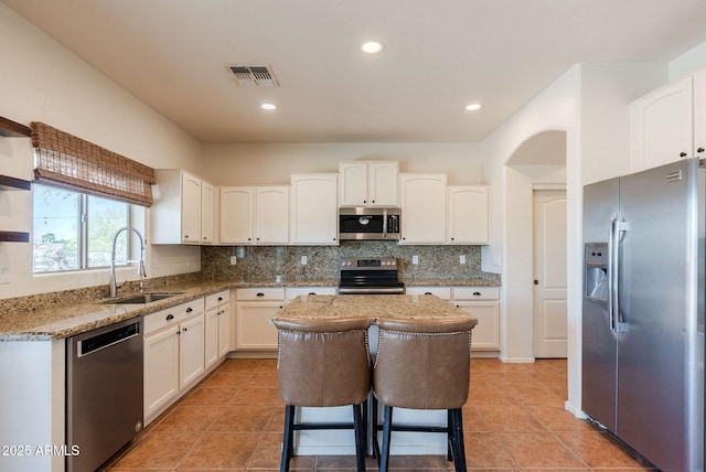 9998 W Prospector Dr, Queen Creek, AZ 85144 - kitchen featuring stainless steel appliances, a sink, light stone counters, decorative backsplash, and white cabinetry