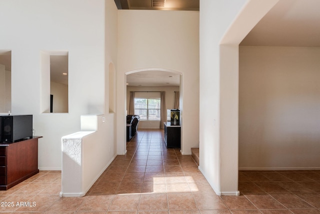 9998 W Prospector Dr, Queen Creek, AZ 85144 - hallway with arched walkways, light tile patterned floors, a high ceiling, and baseboards