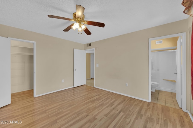 unfurnished bedroom with ceiling fan, light hardwood / wood-style flooring, ensuite bathroom, a walk in closet, and a closet