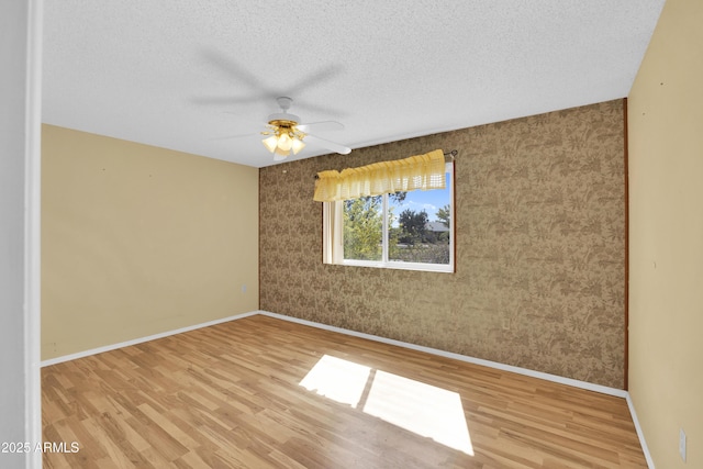 empty room featuring a textured ceiling, light hardwood / wood-style flooring, and ceiling fan