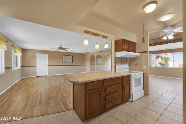 kitchen with pendant lighting, ceiling fan with notable chandelier, light tile patterned floors, white electric range oven, and kitchen peninsula