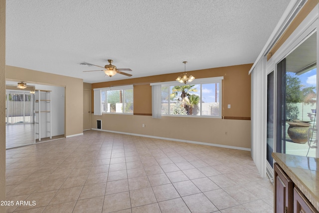 tiled empty room featuring a textured ceiling and ceiling fan with notable chandelier