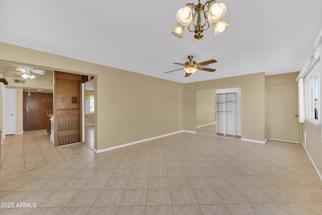 spare room featuring ceiling fan with notable chandelier, light tile patterned floors, and a textured ceiling