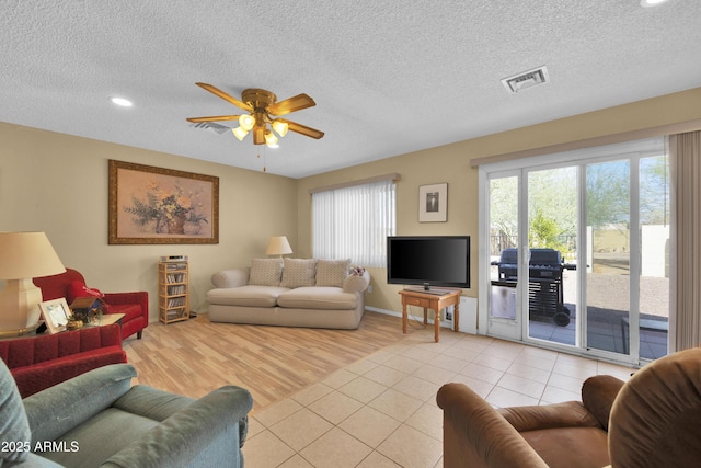 living room with ceiling fan, light tile patterned floors, and a textured ceiling