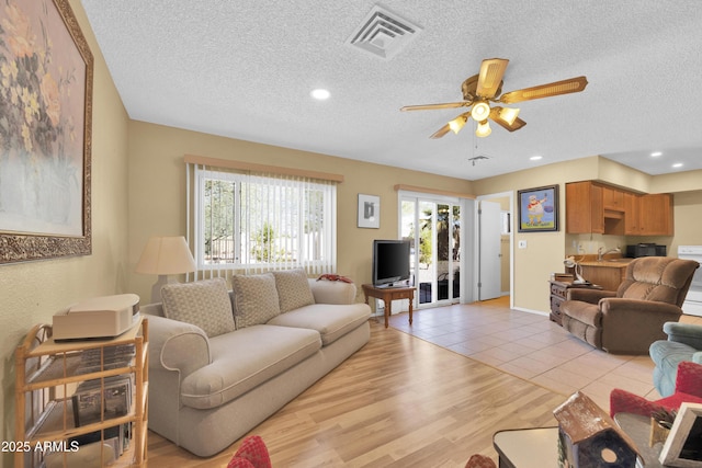 tiled living room featuring ceiling fan and a textured ceiling