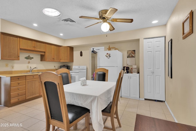 tiled dining space featuring washer / clothes dryer, ceiling fan, sink, and a textured ceiling