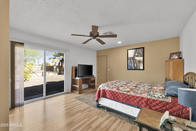 bedroom featuring access to outside, ceiling fan, hardwood / wood-style floors, and a textured ceiling