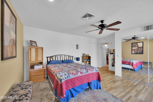 bedroom featuring ceiling fan, a closet, wood-type flooring, and a textured ceiling