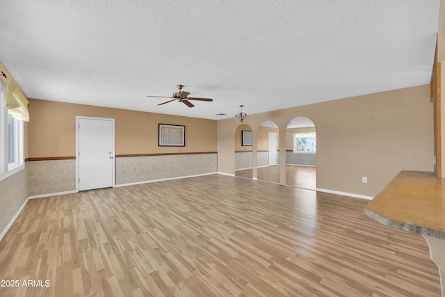 unfurnished living room featuring a textured ceiling, light hardwood / wood-style floors, and ceiling fan