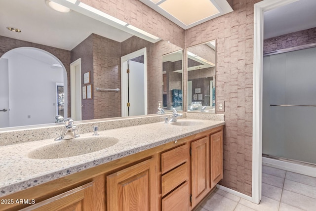 bathroom featuring tile patterned floors, a shower stall, double vanity, and a sink