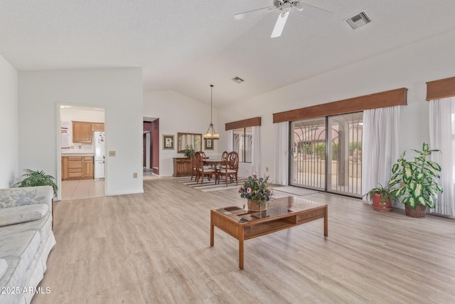 living area with ceiling fan, visible vents, lofted ceiling, and light wood-style flooring