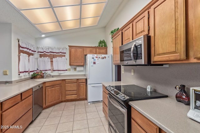 kitchen with light tile patterned floors, stainless steel appliances, light countertops, and a sink