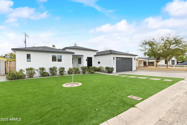 view of front facade with fence, stucco siding, a front lawn, concrete driveway, and a garage