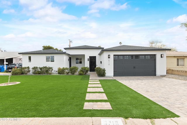 prairie-style house featuring a front lawn, decorative driveway, an attached garage, and stucco siding