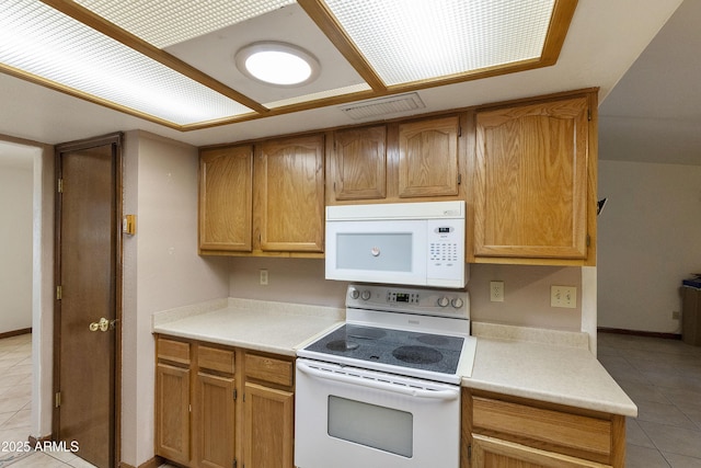 kitchen featuring light tile patterned floors, visible vents, white appliances, and light countertops