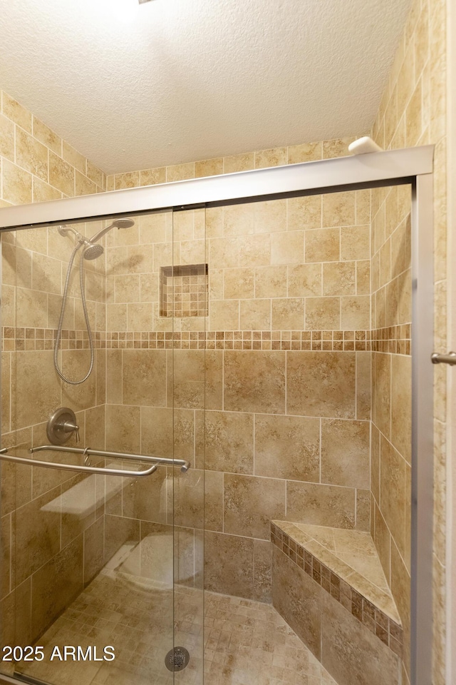 bathroom featuring a shower stall and a textured ceiling
