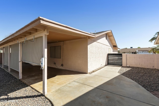 exterior space with stucco siding, a carport, and fence